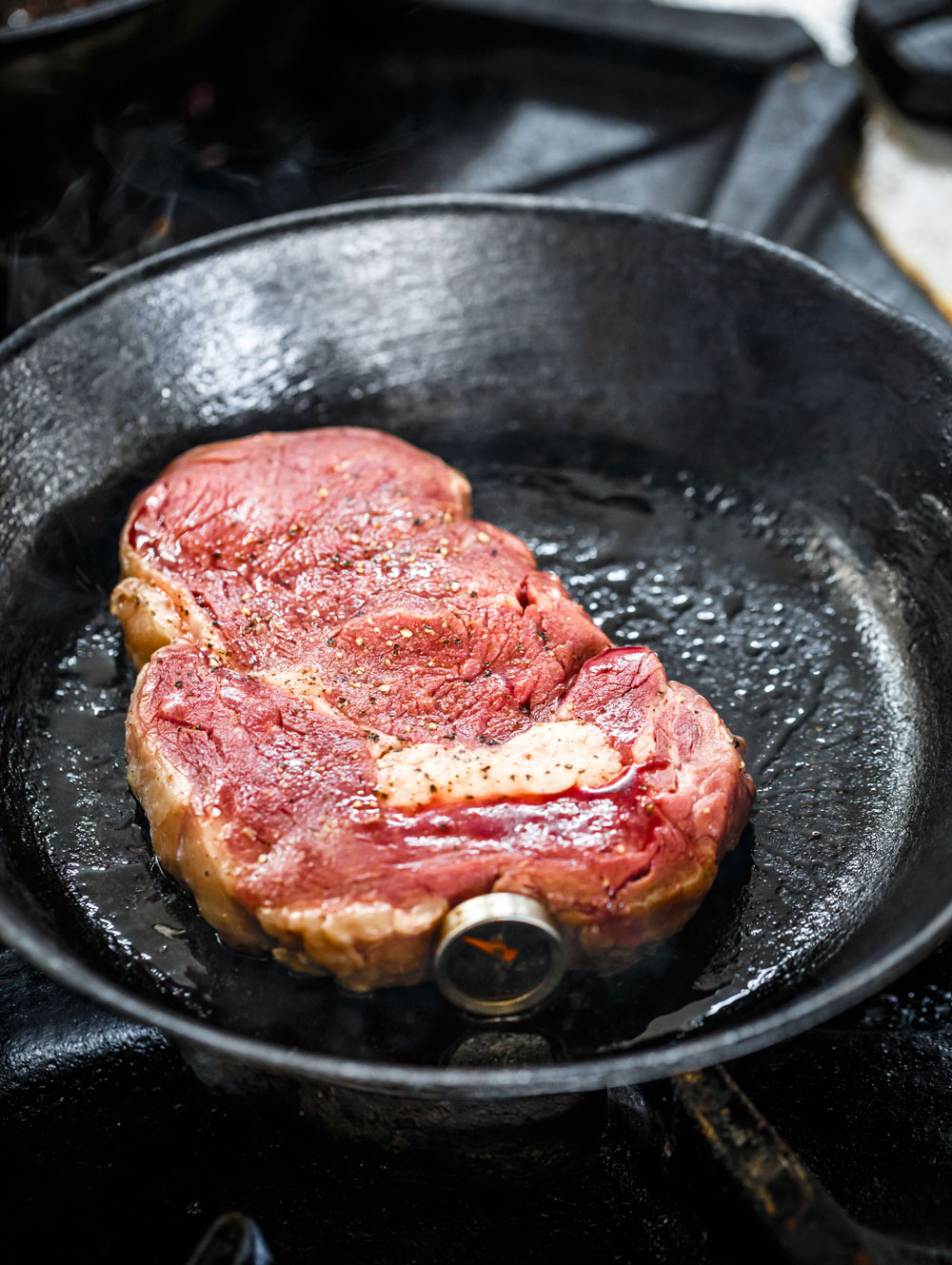 Steak in a skillet with a meat thermometer